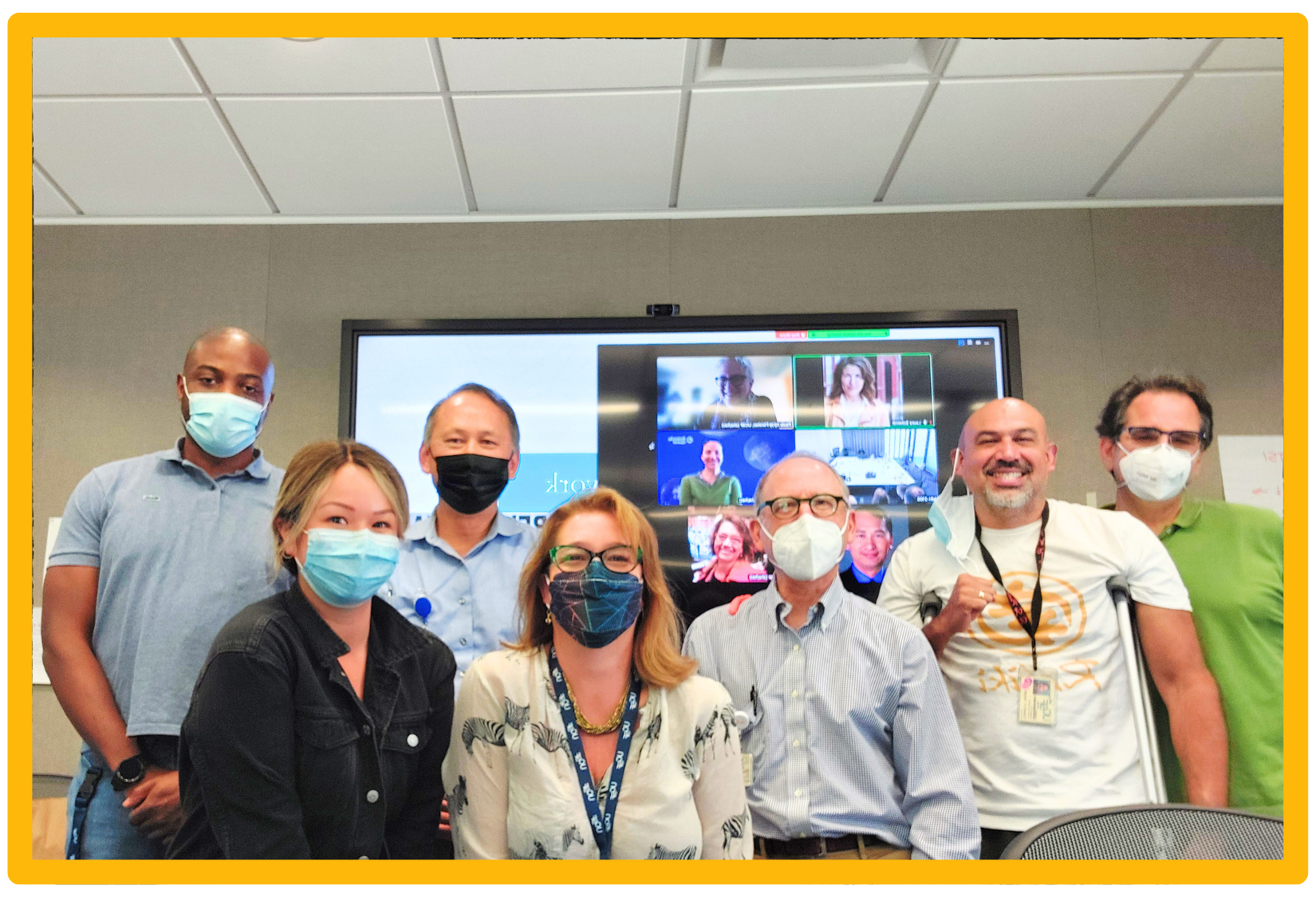 Group of 7 people in an office smiling.